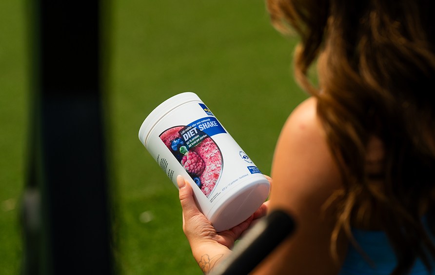 En kvinde holder en btte Diet Shake.